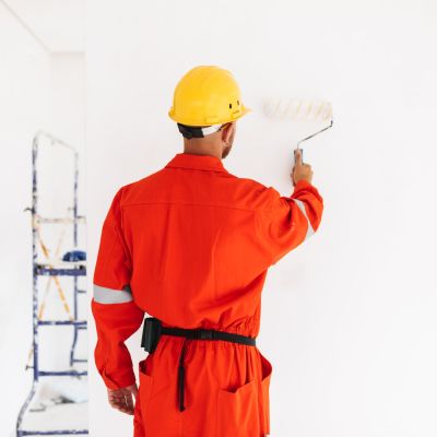 Young foreman standing from back in orange work clothes and yell